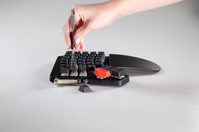 keycaps being removed by the appropriate tool, the tool being squeezed